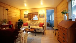 L’intérieur d’un chalet en bois chaleureux et accueillant, avec un canapé, une table basse, une commode et un miroir.