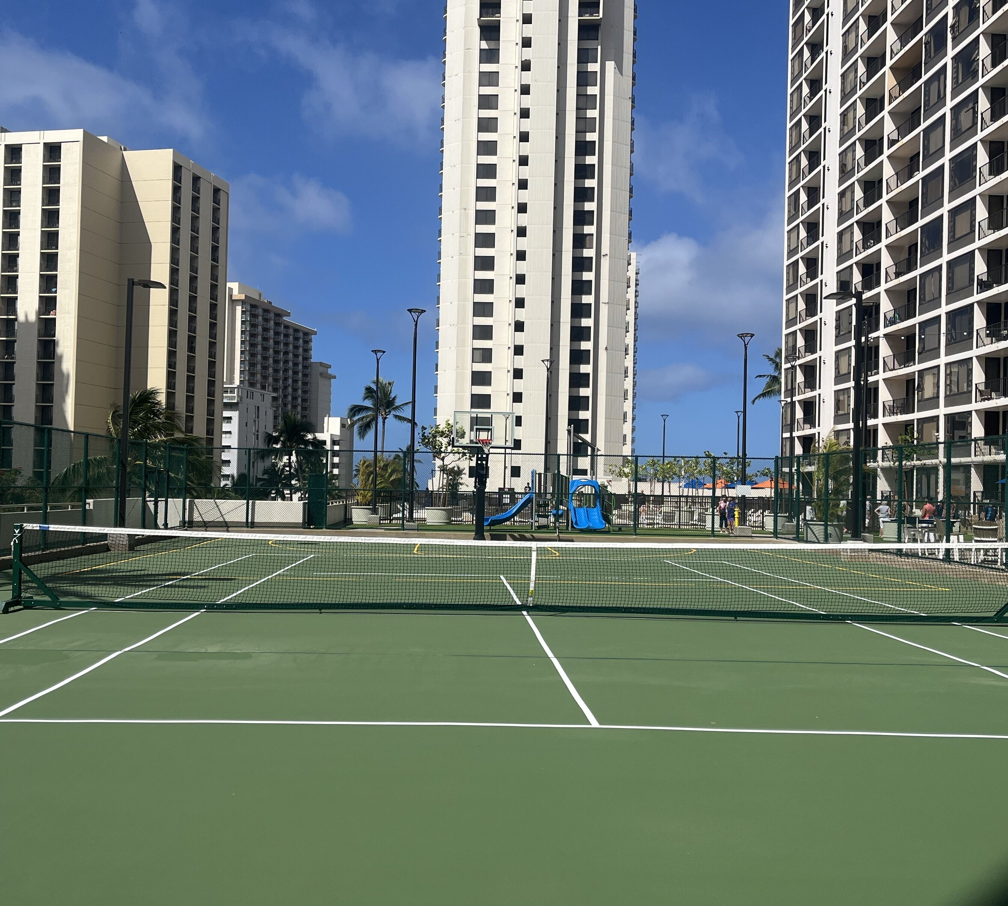 A tennis court surrounded by tall residential buildings.
