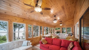 L’intérieur d’un chalet en bois, avec un canapé rouge, un canapé blanc et une table à manger.