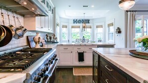 A spacious kitchen with white cabinets, a large island, and a 'HOME' sign above the windows.