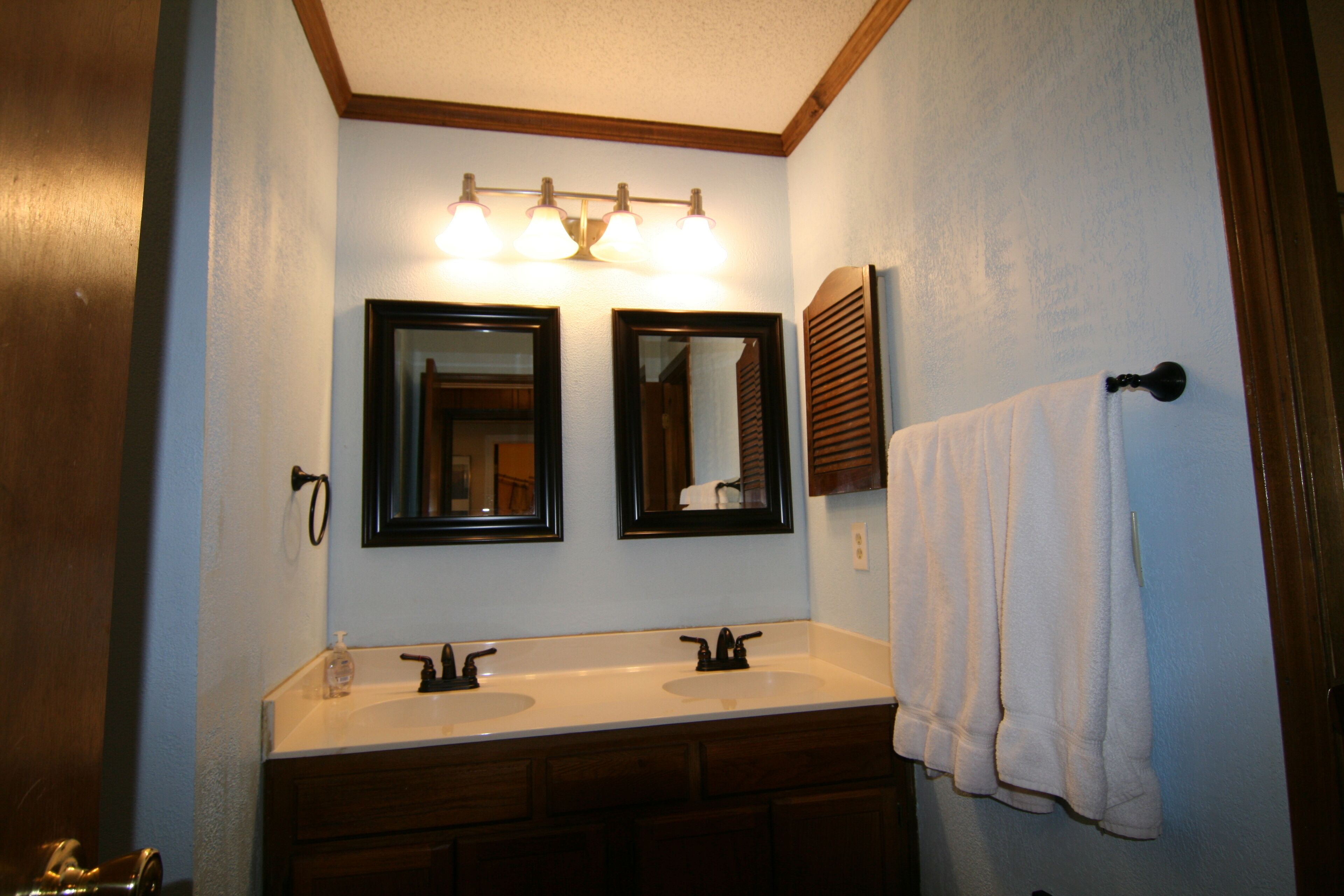 Une salle de bain avec deux lavabos, un miroir et un porte-serviettes.