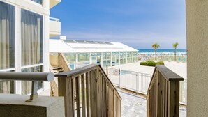 Un escalier en bois mène à une zone de plage équipée d’une piscine et offrant une vue sur l’océan.