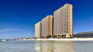 A beachfront hotel with multiple high-rise buildings, clear blue sky, and calm sea. - SPLASH RESORT 7th flr 1/2 Gulf Front w Bunks, Kids Waterpark, Free Beach Chairs (Panama City Beach)