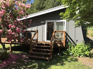 Ein Haus mit einer Veranda, einer Holzbank und einem Blumenbeet.