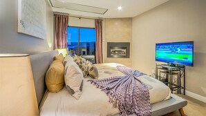 A hotel room with a bed, a television, a window with curtains, and a view of the outdoors. - Spacious 2-Bedroom + 3-Bath Condo | 200 Yards from the Slopes! (Steamboat Springs)