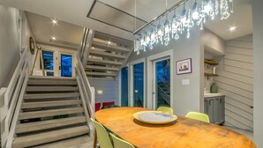 A modern dining area with a wooden table, chairs, and a staircase. - Spacious 2-Bedroom + 3-Bath Condo | 200 Yards from the Slopes! (Steamboat Springs)