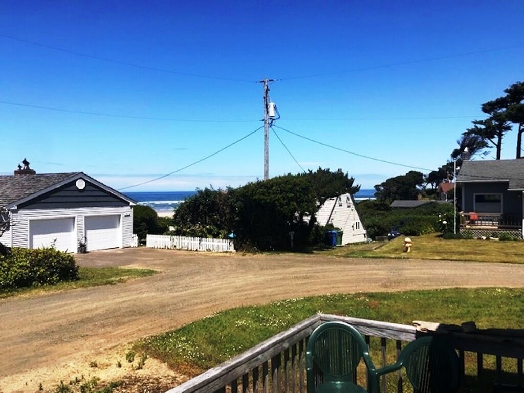 Un quartier résidentiel avec un chemin de terre, un garage blanc et un poteau électrique avec des lignes électriques.