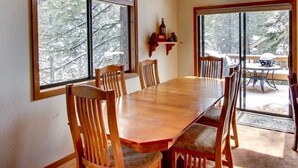 A dining room with a large wooden table and chairs, large windows with a view of trees, and a chandelier. - Family-Friendly, Pet-Friendly, Tree-Surrounded Tahoe City Vacation Home (Tahoe City)