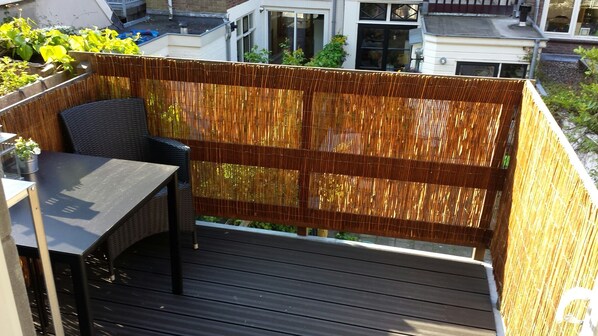 Une terrasse en bois avec une table et des chaises, entourée d’une clôture en bambou.