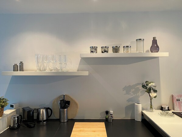 Een moderne keuken met een houten aanrecht, koffiezetapparaat, waterkoker en een hangmand.