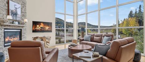 Picture yourself curled up on plush leather sofas, fireplace crackling beside you, as floor-to-ceiling windows frame stunning mountain and forest vistas stretching beyond your private retreat.