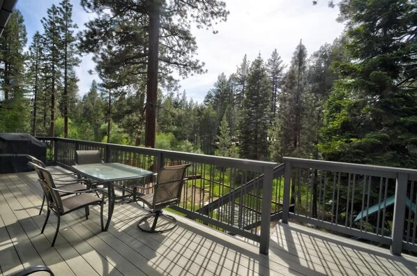 A deck with a table and chairs, surrounded by a railing, overlooking a forested area. - 1 Family Paradise, Den, Playground, Space (South Lake Tahoe)