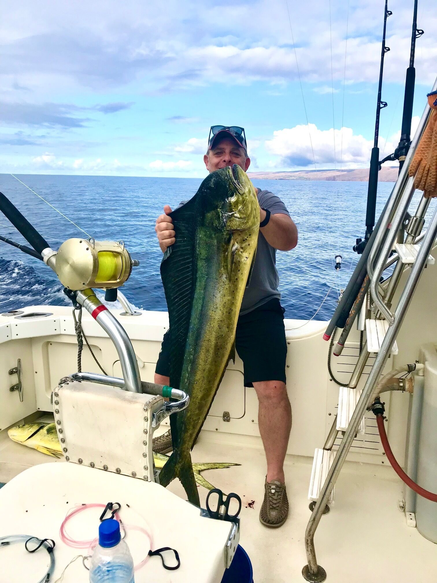 Eine Person hält einen großen Fisch auf einem Boot, im Hintergrund der Ozean.
