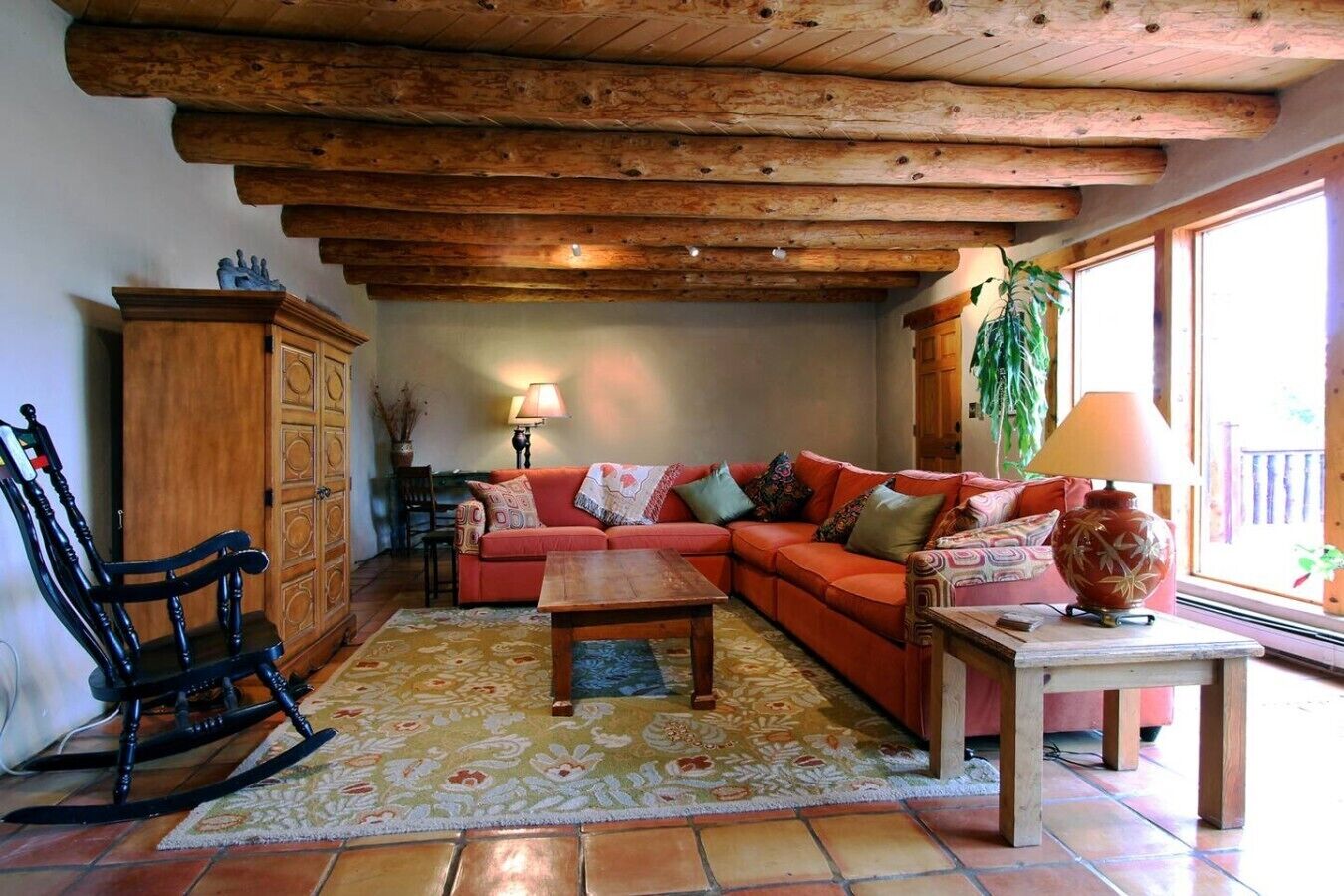 Un salon chaleureux avec un plafond en bois, un canapé, un fauteuil à bascule et une table.
