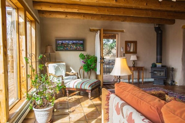 A cozy living room with a fireplace, a sofa, a chair, and a potted plant.