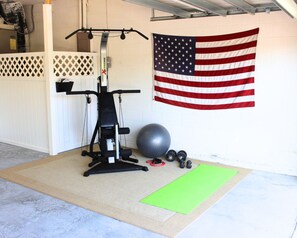 A home gym with a weight bench, a squat rack, a large exercise ball, and dumbbells. - Dog friendly! Super Quiet, Pool, Close to Disney, Indoor Game Room, 2 Masters (Davenport)