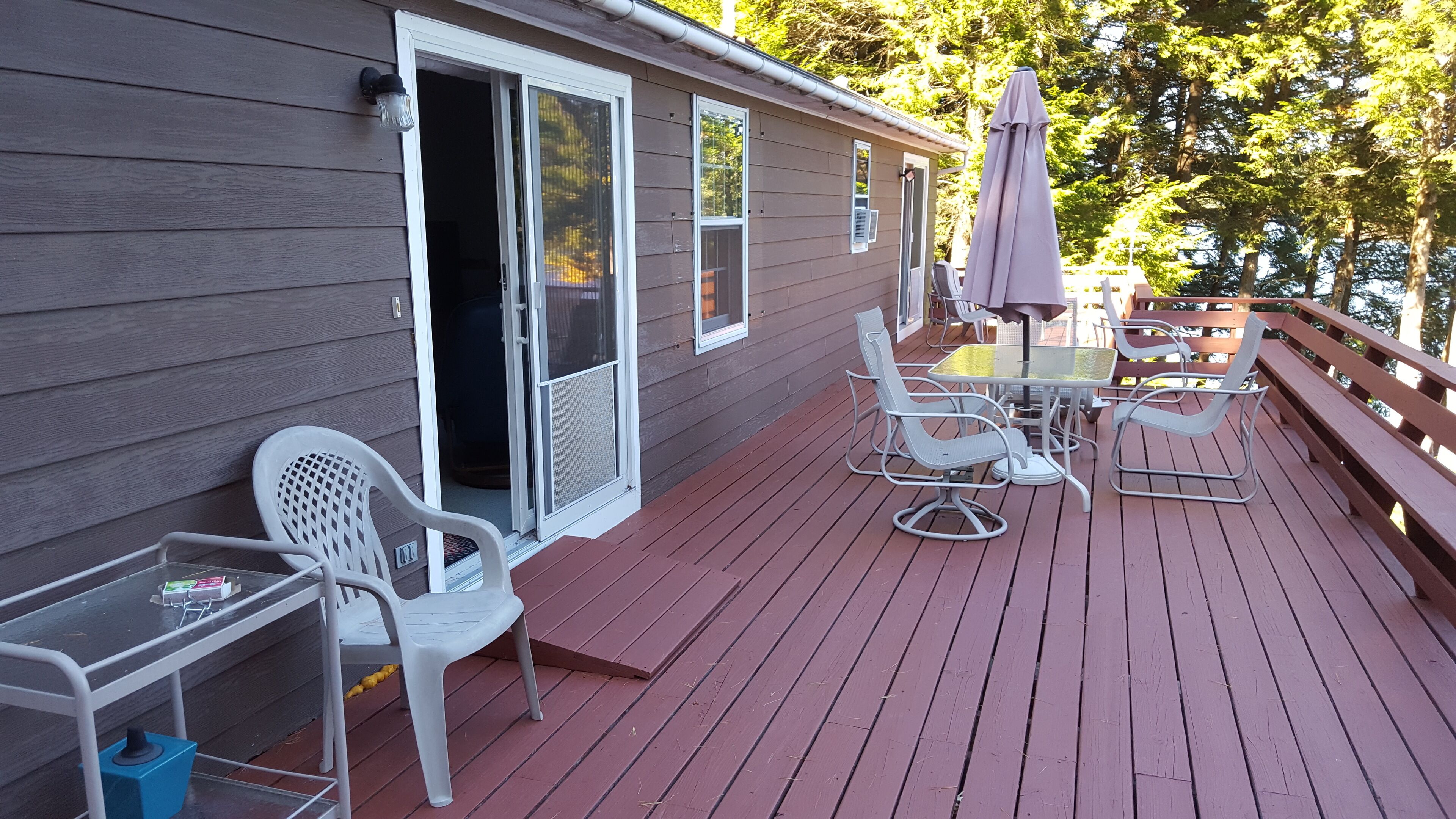 A wooden deck with outdoor furniture, a sliding glass door, and a patio umbrella.