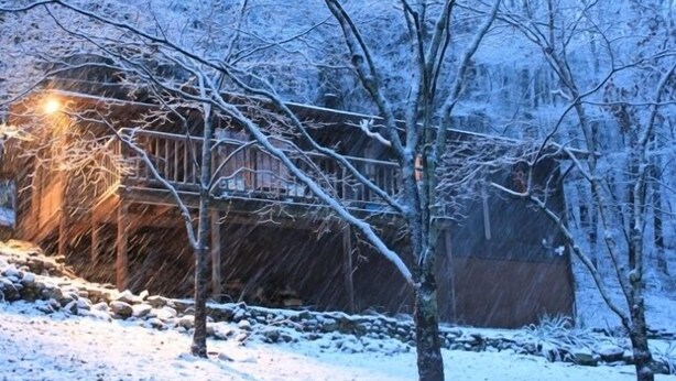 A snow-covered landscape with a wooden cabin and a stone wall. - Secluded Mountain Cabin, Lakefront, Hiking, Fishing, Relaxing (Syria)