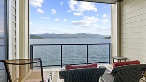 A balcony with wicker furniture and a view of a lake and mountains. - Balcony, Beach & Bliss- Seasons at Sandpoint (Sandpoint)