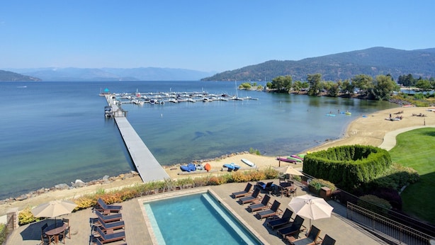 A resort with a swimming pool, lounge chairs, and a view of the lake and dock. - Balcony, Beach & Bliss- Seasons at Sandpoint (Sandpoint)