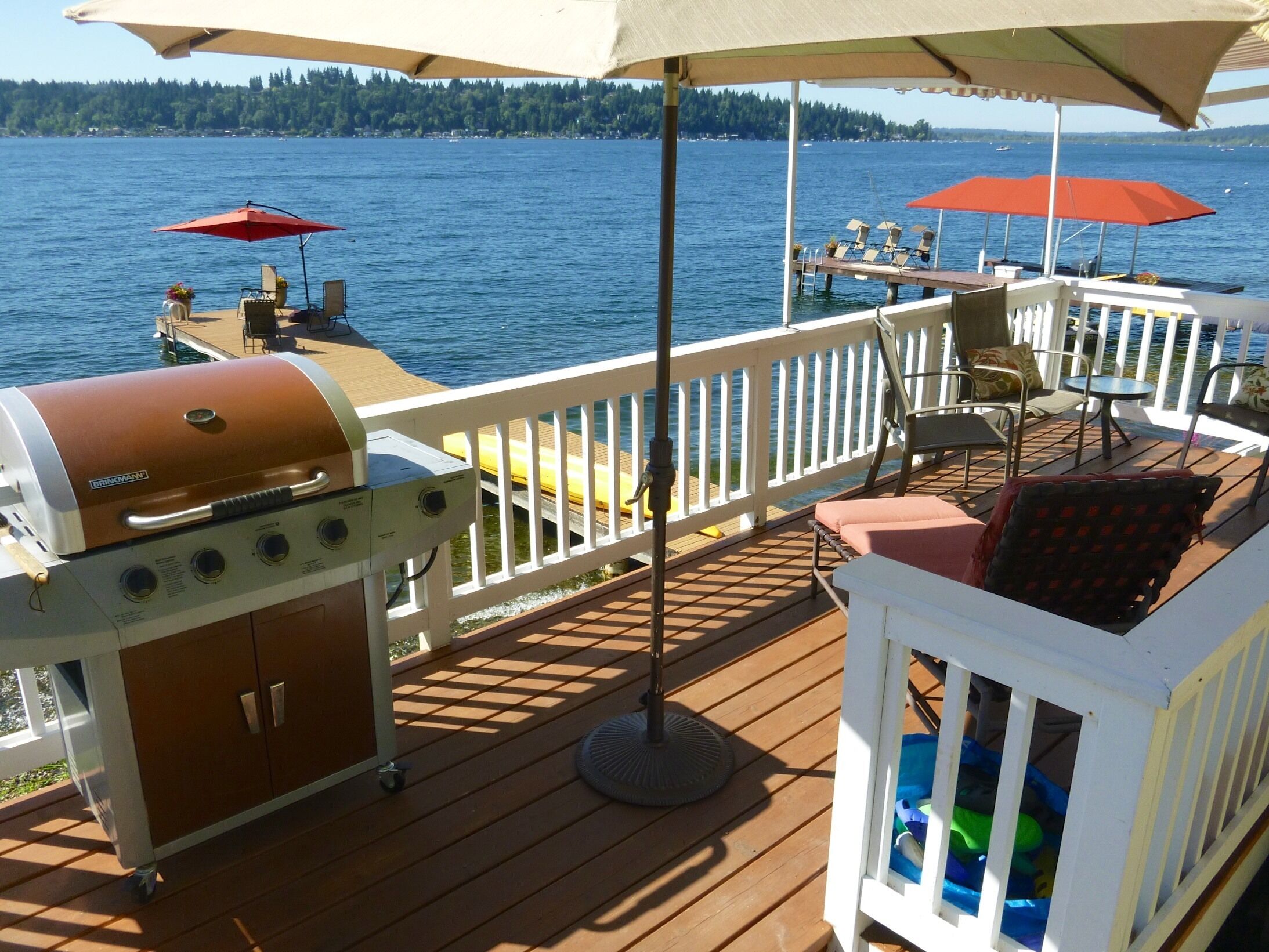 Una terraza con parrilla, asientos al aire libre y vista al agua.