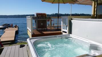 Relax by the water's edge on our serene deck, featuring a hot tub and outdoor dining area.