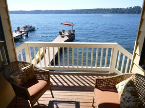 A wooden deck with wicker furniture and a view of a lake with boats.