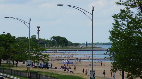A beach with a pedestrian walkway, street lamps, and a speed limit sign.