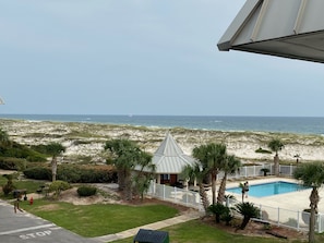 Enjoy ocean views from this beachfront property, featuring a pool, a charming building, and a fenced area with palm trees.