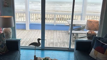 Un salon avec vue sur la plage, une table basse en bois et deux canapés.