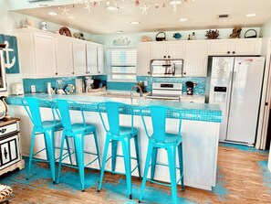A kitchen with a central island, white cabinets, and blue chairs.