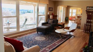 A spacious living room with a large window, a patterned rug, and a variety of seating options. - Treetop Lodge - Lose yourself in the views on the westside, close to downtown. (Paso Robles)