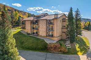 A multi-story hotel with a stone facade, balconies, and a well-maintained lawn. - Snowbound Bliss: Slopeside, Hot Tubs & Shuttle (Steamboat Springs)