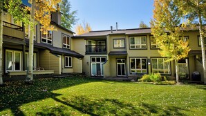 A two-story house with a front porch, a covered patio, and a backyard with a lawn. - Coldstream Townhome 38 | Stylish 3BR Cascade Village Retreat (Vail)