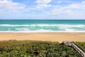 A beach with a wooden boardwalk leading to a structure, overlooking the ocean.