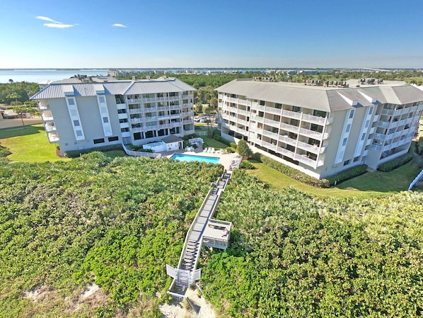 A large hotel with multiple floors, a swimming pool, and a bridge connecting different sections.