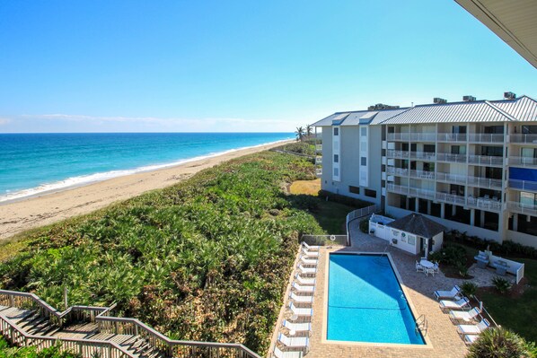 Un hotel con piscina, vista al mar y varios balcones.