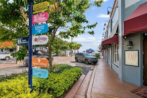 A street with a signpost listing various businesses including a cafe, a clothing store, and a boutique.