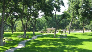 A park with picnic tables, a walking path, and a building in the background. - Treetop Retreat on the Guadalupe Ultra Private 3rd Floor End Unit (New Braunfels)
