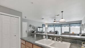 A kitchen with a double sink, wooden cabinets, a countertop, and a ceiling fan. - Treetop Retreat on the Guadalupe Ultra Private 3rd Floor End Unit (New Braunfels)