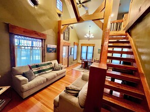 A spacious living area with a wooden staircase, a sofa set, and a dining table. - Entire house in small town Manhattan, Montana. (Manhattan)