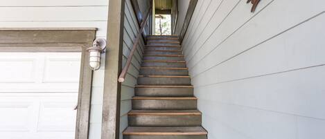 A wooden staircase leading to a garage door with a 'TEN' sign above it.