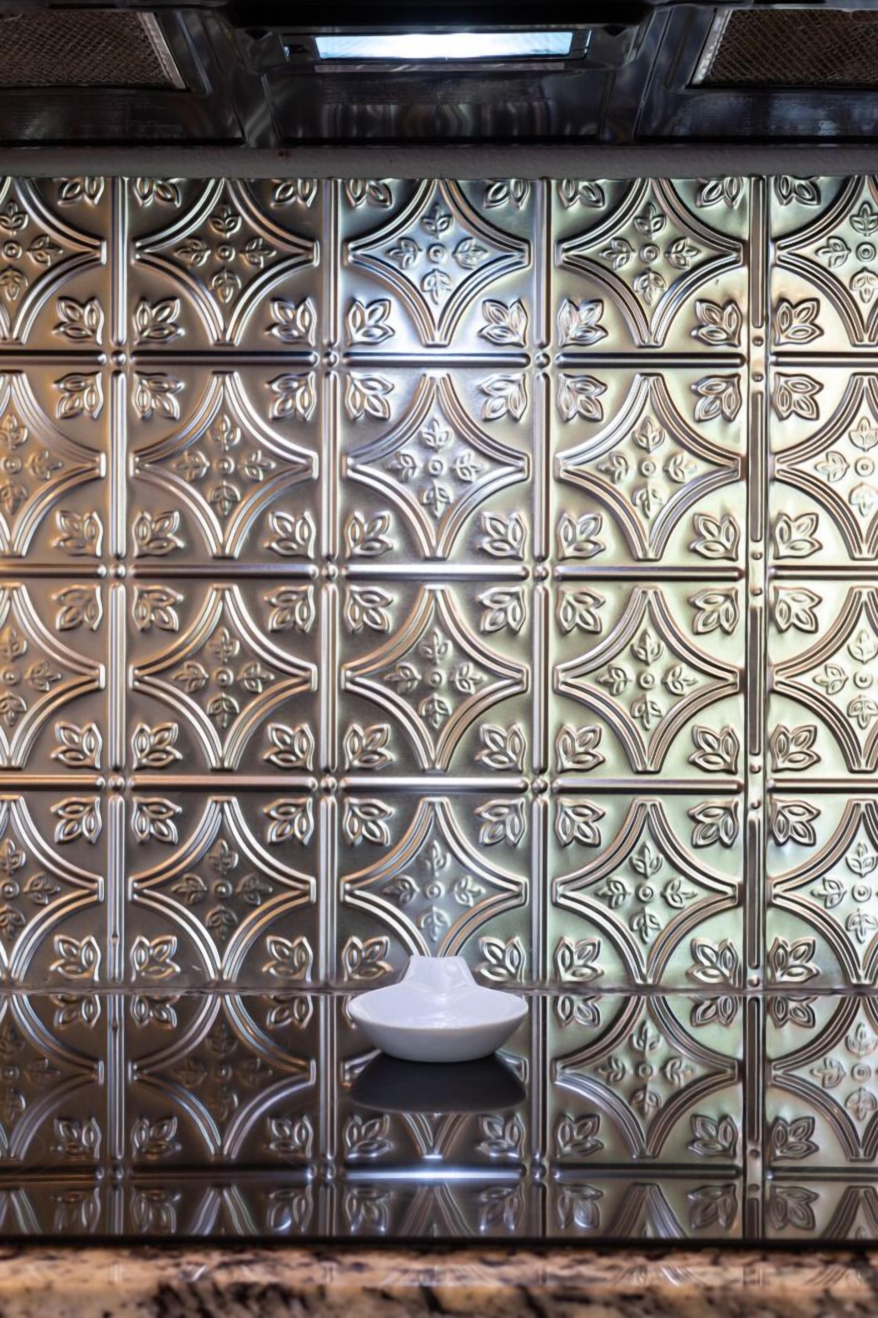 Een badkamer met decoratieve metalen wandpanelen en een witte wastafel.