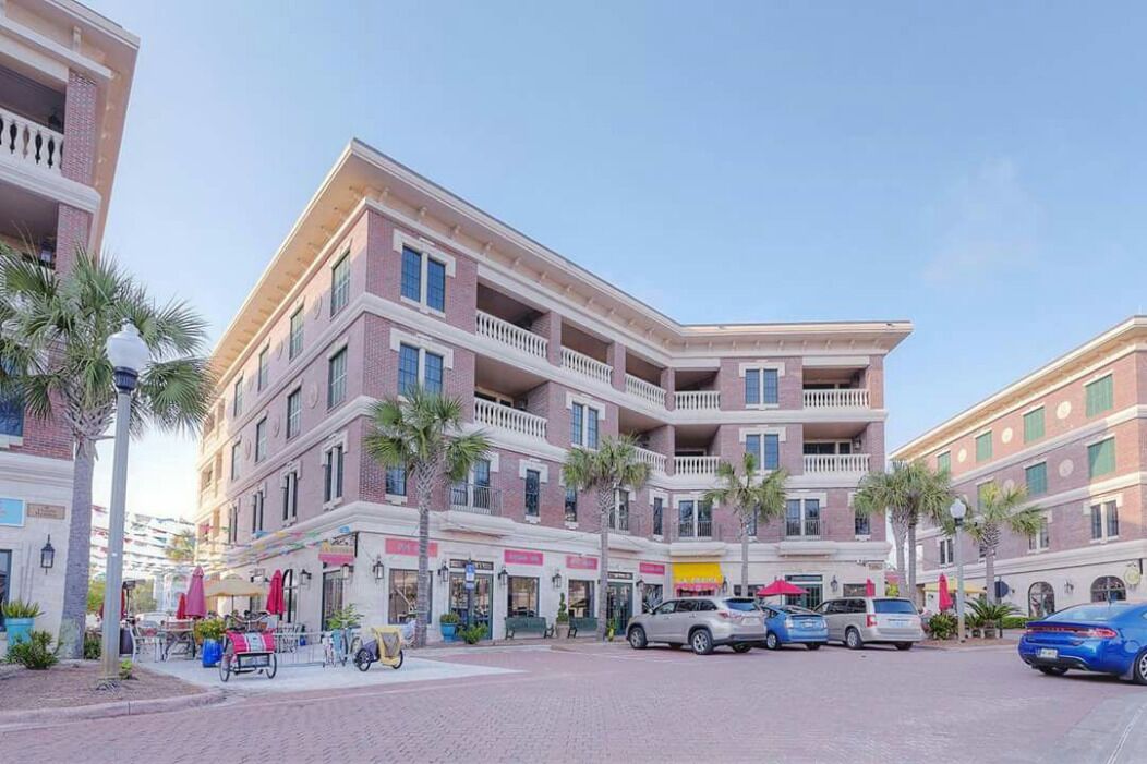 A multi-story hotel with balconies, a paved street, and parked cars.