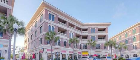 A multi-story hotel with balconies, a paved street, and parked cars.