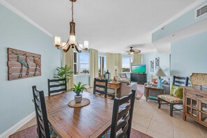 A spacious living area with a dining table, chairs, a TV, and a ceiling fan.