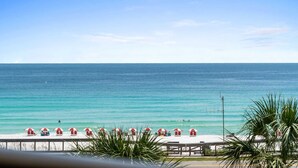 Una spiaggia con ombrelloni rossi e bianchi, una riva sabbiosa e l'oceano.