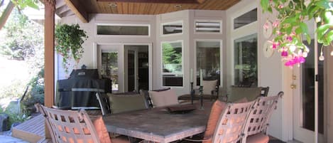 An outdoor patio with a wooden deck, a table with chairs, and a grill.