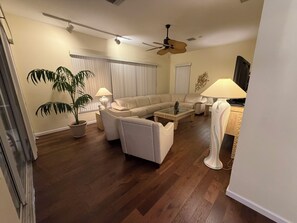 A living room with a sofa, armchairs, a coffee table, a ceiling fan, a potted plant, and a lamp. - TOP Rated Premium Costal Family Retreat with Heated Pool & Private Golden Beach (Venice)