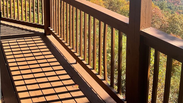 A wooden deck with a view of a forested mountain range.